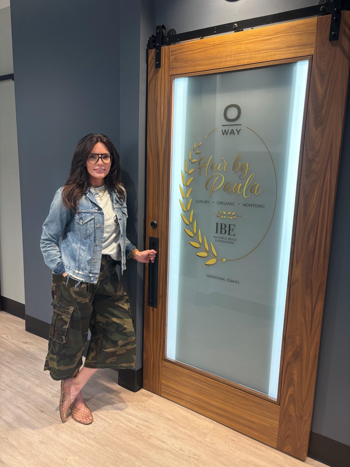 Paula Bennett beside the Hair by Paula OWAY and IBE salon door in Meridian, Idaho